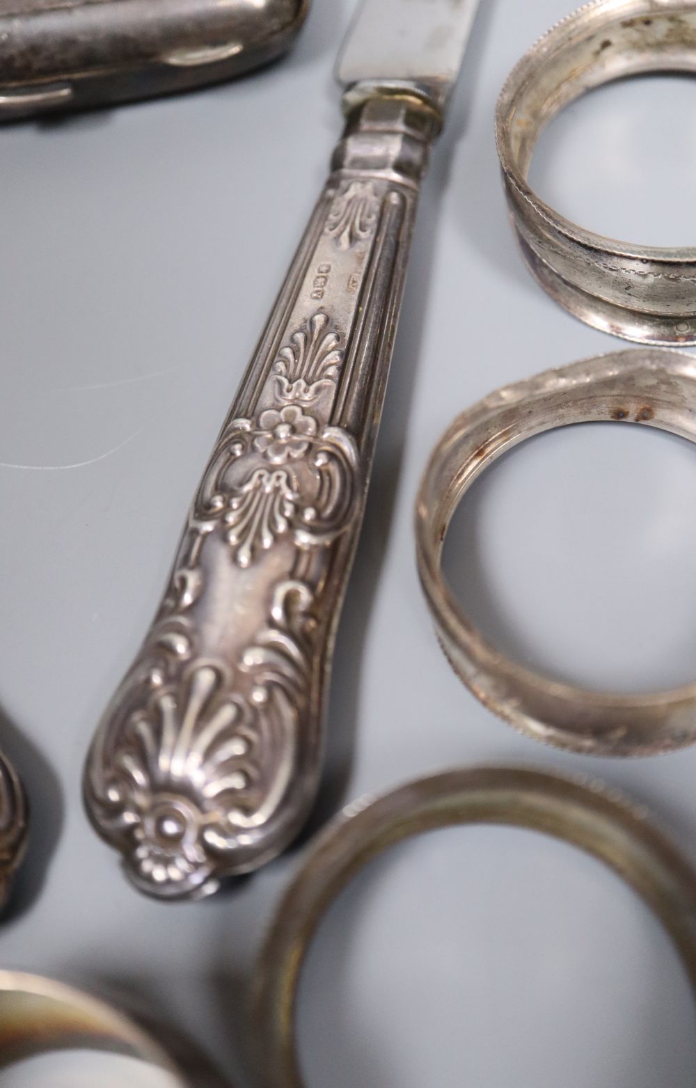 Nine assorted silver napkin rings, a pair of silver pepperettes, a silver cigarette case and pair of silver handled servers.